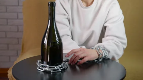 Person chained to wine bottle symbolizing alcohol addiction Stock Footage 334784796