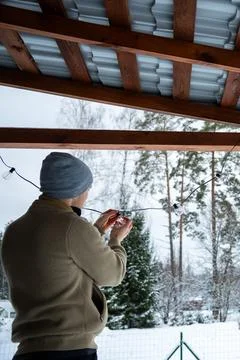 Person Changing LED Bulbs Under Wooden Terrace Roof in Winter Stock Photos