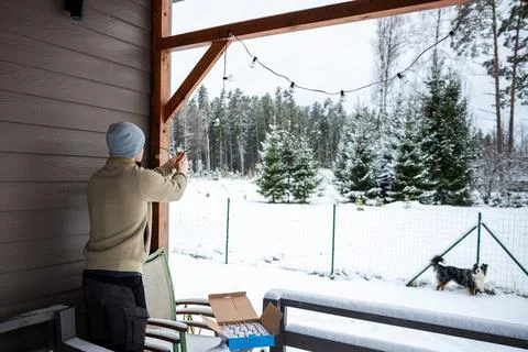 Person Changing LED String Lights on Snowy Terrace in Winter Stockfoto's