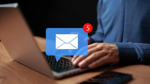 Person checking emails on a laptop while sitting at a wooden table at night Stock Photos