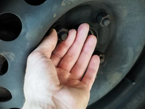 Person checking rusty nuts and bolts on wheel Stock Photos