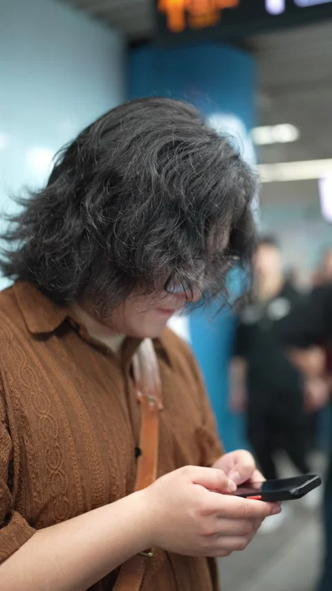 Person checks a smartphone in a crowded concourse Video stock 344039311