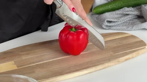 A person chopping a red bell pepper on a wooden cutting board. Vidéo 340526472