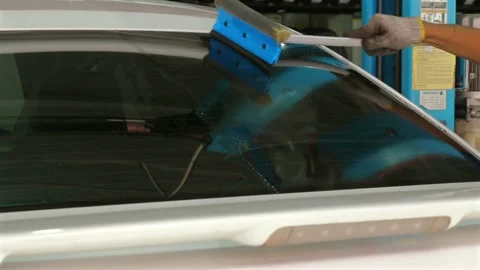 Person cleaning car windshield with squeegee at car wash, close-up Stock Footage 283999174