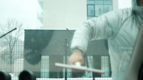 Person cleaning car windshield with squeegee at car wash, close-up of hands and Stock Footage 297702873