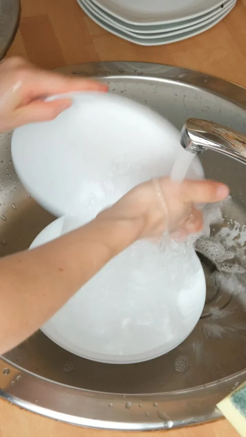 Person cleaning dish with soapy foam sponge under kitchen faucet. Stock Footage 344037708