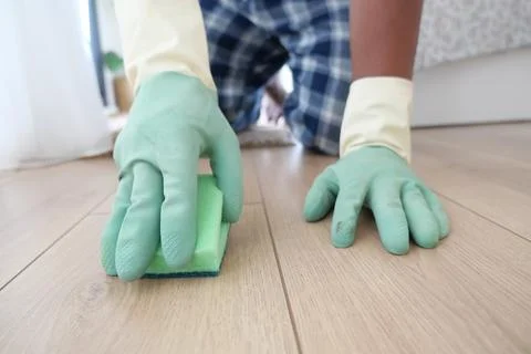 Person cleaning the floor with a sponge while wearing gloves indoors Stock Photos