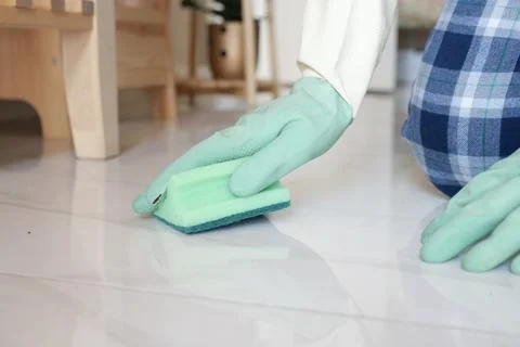 Person cleaning the floor with a sponge while wearing gloves at home Stock Photos