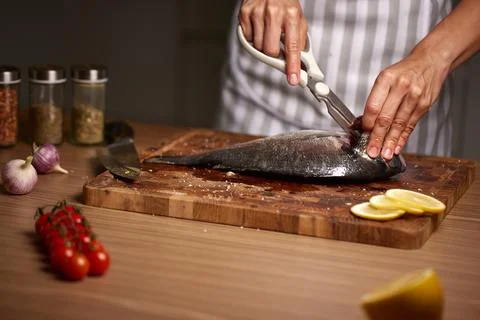 Person cleaning raw fish using kitchen scissors 写真素材