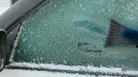 A person cleaning the side windows of a car from snow with ice scraper. Stock Footage 296096629