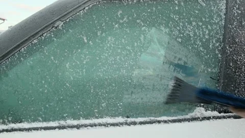 A person cleaning the side windows of a car from snow with ice scraper Stock Footage 296478249