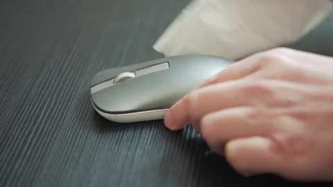 Person cleaning sleek computer mouse with tissue on dark wood surface Stockbeeldmateriaal 347148282