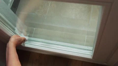 Person cleaning a window with a squeegee in a modern home during daytime near a  Video stock 331742765
