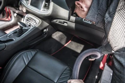Person Cleans Car Interior Using Vacuum in Bright Sunlight at a Parking Lot Photos