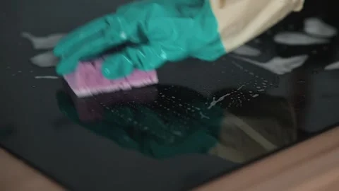 A person cleans a glass surface using a sponge and cleaning solution. The action Stockbeeldmateriaal 337111898