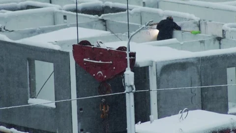 Person clearing snow from modular concrete structures, red crane hook in Video stock 342922883