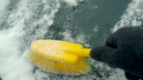 Person clears windshield quickly. Gloved hand brushes snow off vehicle 動画素材 347325321