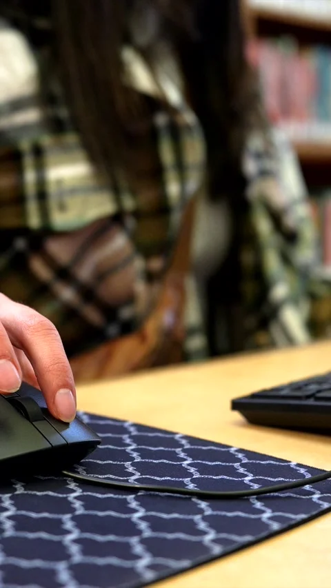 Person clicking and scrolling computer mouse in a library Stock Footage 333105927