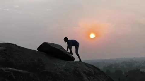 Person Climbing Rock During Sunset with Scenic Landscape Stock Footage 323301360