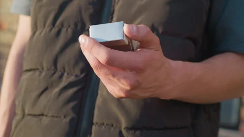 Person closing cigarette pack with thoughtful gesture in front of building Stock Footage 307067433