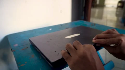 A person closing a laptop computer on a desk, capturing the end of a workda.. Stock Footage 340490058