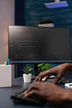 Person coding on computer with green plant Stock Photos