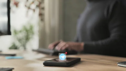 Person at computer receives telegram notification on smart phone Stock Footage 303965672