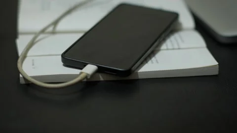 Person Connecting Charging Cable to Smartphone on Desk Stock Footage 345102166