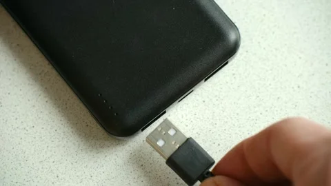 Person connecting usb cable to a black power bank battery Stock Footage 337828232