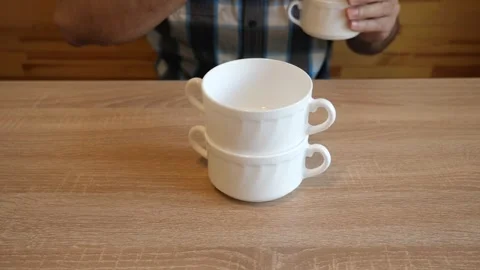 A person continuously stacks ceramic cups one on another, creating distinctiv Stock Footage 341260045