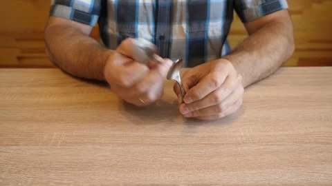 A person continuously taps one metal spoon against another, creating rhythmic Stock Footage 341259622
