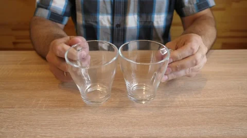 A person continuously taps two glass cups against each other, creating clear  Stock Footage 341259433
