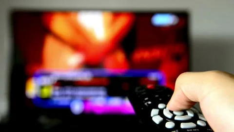 Person controls TV using remote control. Close up view. Blurry tv at the ba.. Stock Footage 257873762
