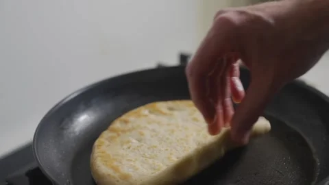 A person is cooking a flatbread in a pan Stock Footage 306043319
