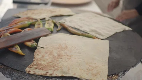 Person Cooking Traditional Flatbread and Peppers on a Hot Griddle Stock Footage 344890437