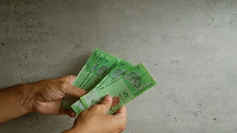 Person counting malaysian ringgit against a concrete wall, showcasing hands.. Stock Footage 291002391