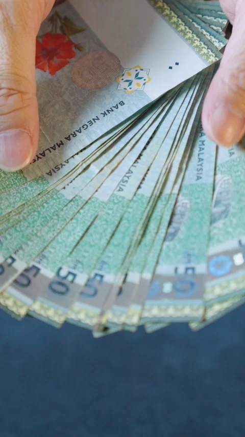 Person is counting a stack of fifty ringgit bills Stock Footage 294286161