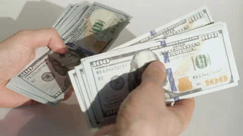 Person counting a stack of hundred-dollar US banknotes Video stock 231558064