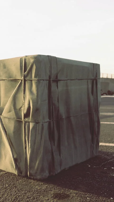 Person covers a large object with a green tarp during sunset at the parking lot Stock-Footage 336581905
