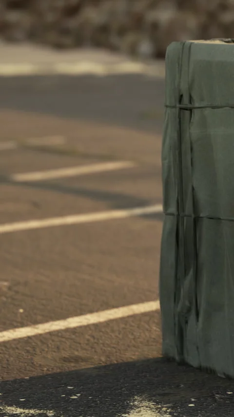 Person covers an object with a green tarp on a parking lot surface Stock-Footage 337940938