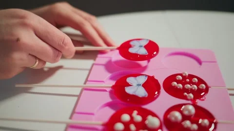 Person crafting decorated lollipops using a pink mold Video stock 336166337