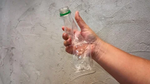 Person Crushing Plastic Water Bottle for Recycling Against Concrete Wall Stock Footage 341925117