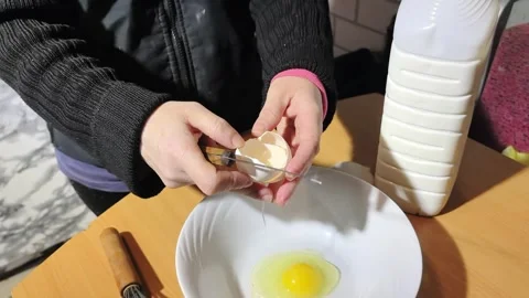 Person cuts egg carefully in kitchen while preparing for meal with bowl and bott Video stock 328446755
