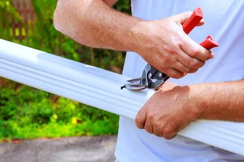 Person cuts plastic pipe material using gardening shears in garden Stock Photos
