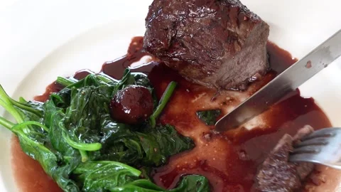 Person cuts into tender braised beef with a knife and fork, served with spi.. Vídeos de archivo 339343867