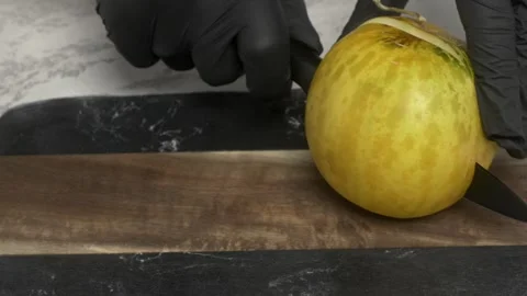 A person cuts a yellow melon in half, showing vibrant colors and textures 動画素材 279835608
