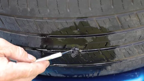 Person cutting access tire plug from a repair of a flat tire Stock Footage 164261790