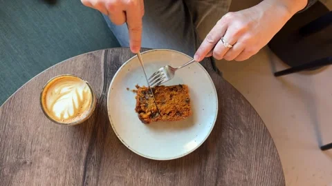 Person cutting and eating slice of cake with coffee on wooden table Stock Footage 337324976