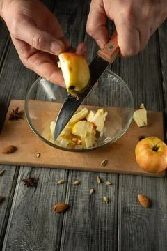 A person is cutting an apple and placing the pieces into a clear bowl. Smal.. Stock Photos