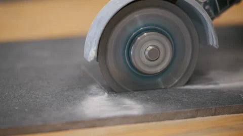 A person is cutting a ceramic tile with an electric grinder on a workbench Stock Footage 334063057